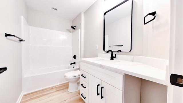 bathroom featuring vanity, toilet, wood finished floors, and shower / bathtub combination