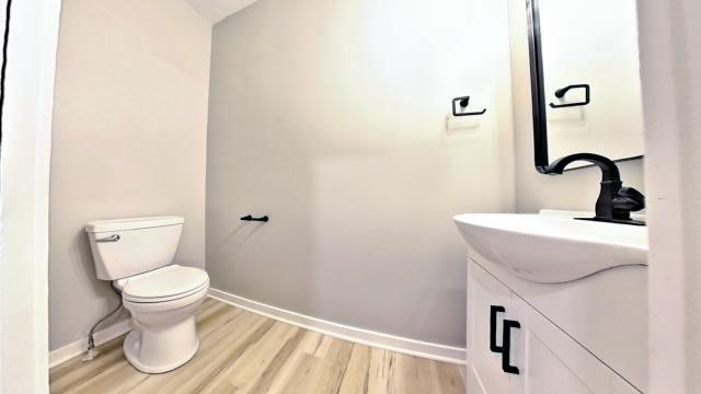 bathroom with vanity, toilet, wood finished floors, and baseboards