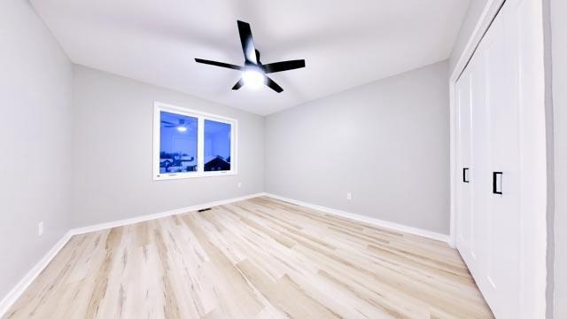 unfurnished bedroom featuring a closet, baseboards, light wood-style floors, and a ceiling fan