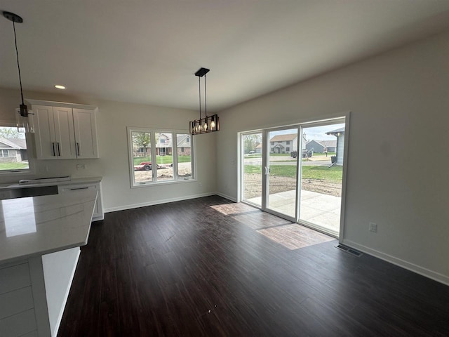 unfurnished dining area with visible vents, baseboards, a notable chandelier, recessed lighting, and dark wood-type flooring