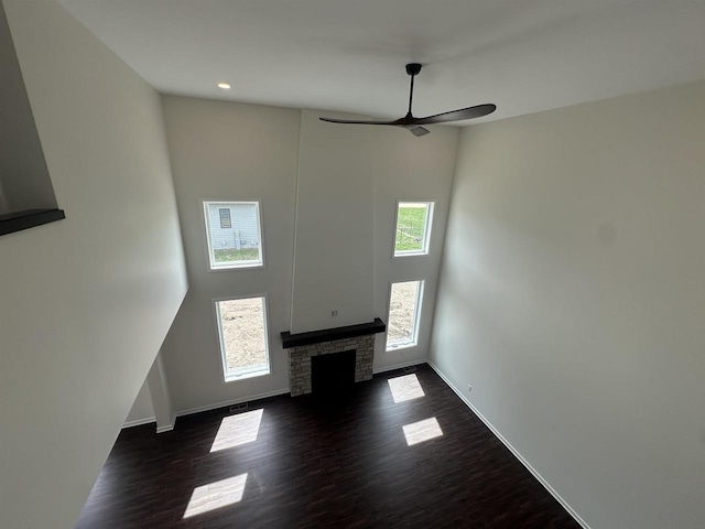 unfurnished living room with a towering ceiling, a ceiling fan, baseboards, and dark wood-type flooring