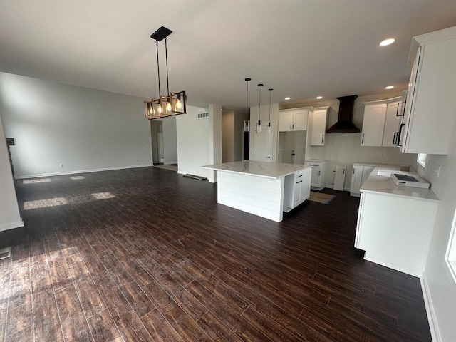 kitchen featuring wall chimney range hood, white cabinets, dark wood-style floors, and open floor plan