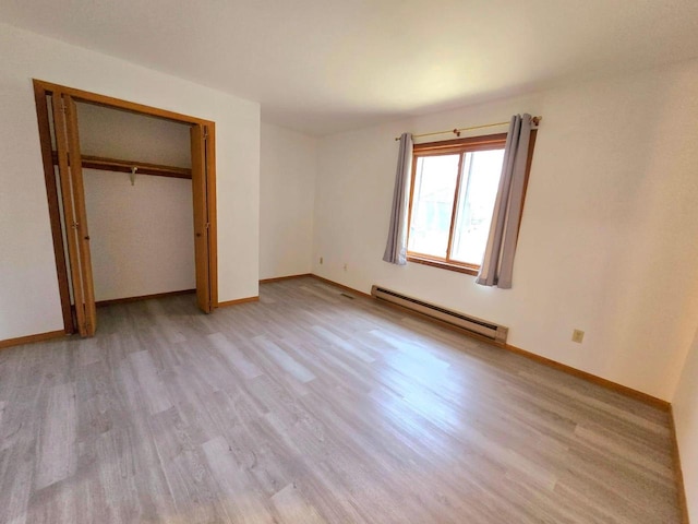 unfurnished bedroom with light wood-type flooring, a baseboard radiator, and a closet