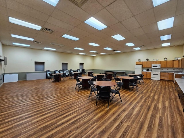 dining space with dark hardwood / wood-style flooring, sink, and a drop ceiling