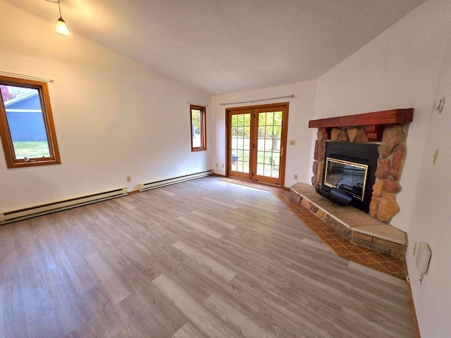 unfurnished living room with hardwood / wood-style floors, a fireplace, a baseboard radiator, and lofted ceiling