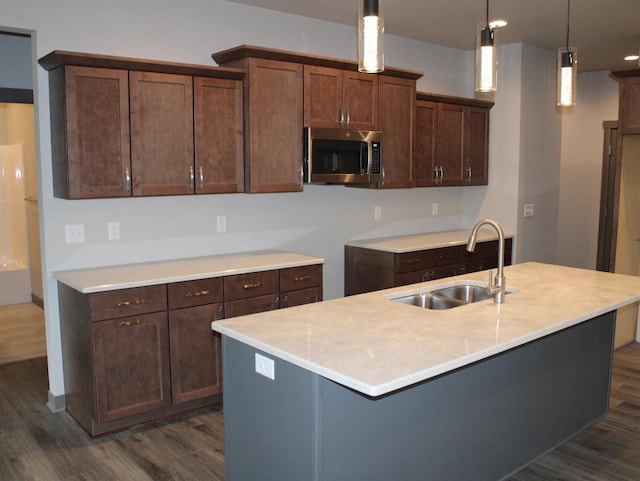 kitchen with sink, an island with sink, pendant lighting, and dark hardwood / wood-style floors