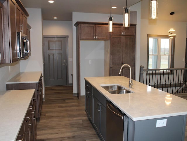 kitchen with decorative light fixtures, stainless steel appliances, sink, and an island with sink