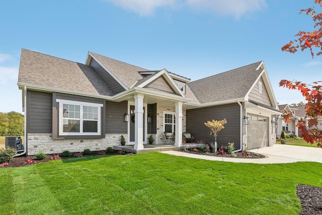 craftsman-style home featuring covered porch, a garage, central air condition unit, and a front yard