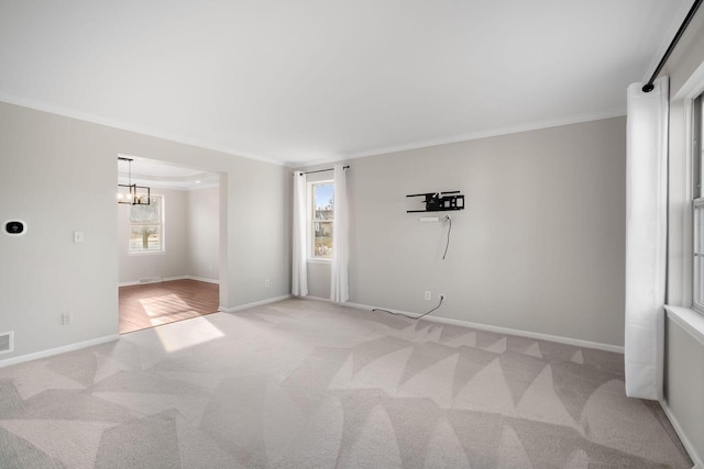 spare room featuring light colored carpet, crown molding, and a notable chandelier