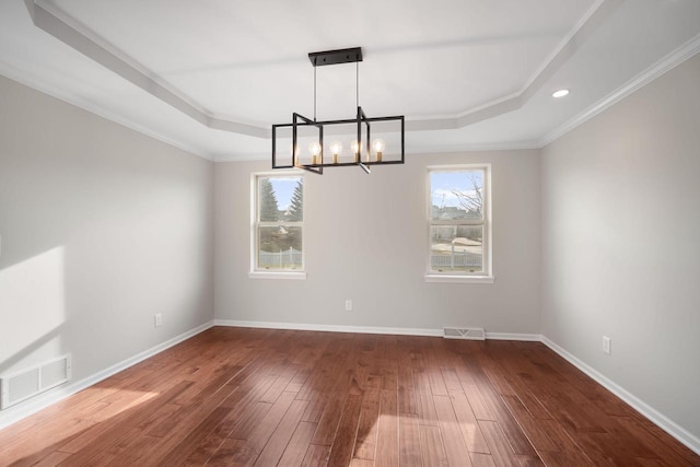 unfurnished room with a tray ceiling, dark wood-type flooring, a chandelier, and ornamental molding