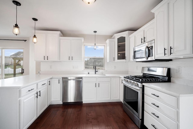 kitchen featuring decorative light fixtures, white cabinetry, kitchen peninsula, and stainless steel appliances