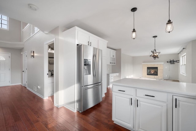 kitchen featuring white cabinets, dark hardwood / wood-style floors, a stone fireplace, and stainless steel refrigerator with ice dispenser