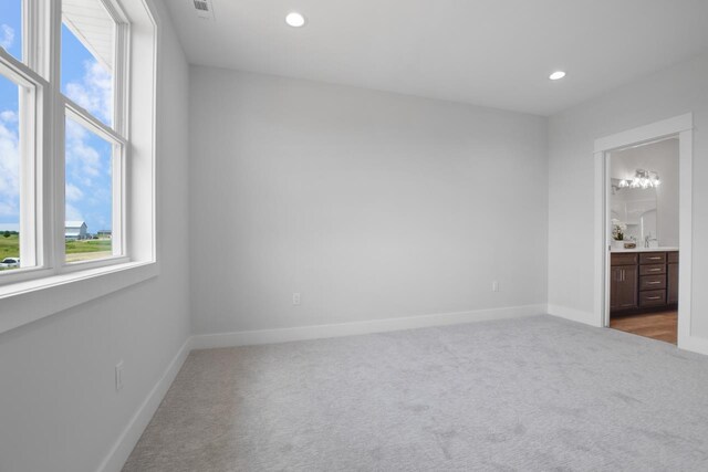 unfurnished bedroom featuring connected bathroom, sink, and carpet