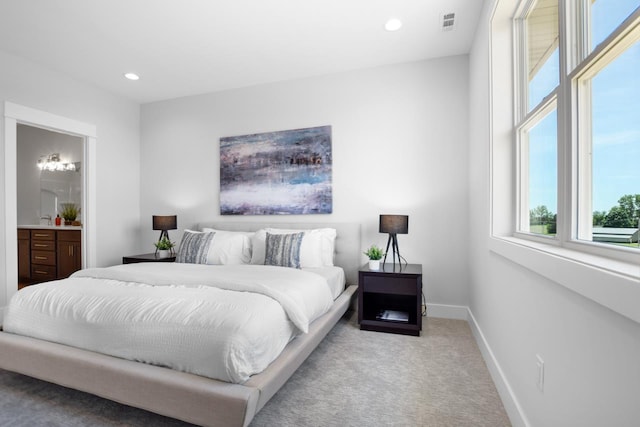 bedroom featuring light colored carpet and connected bathroom