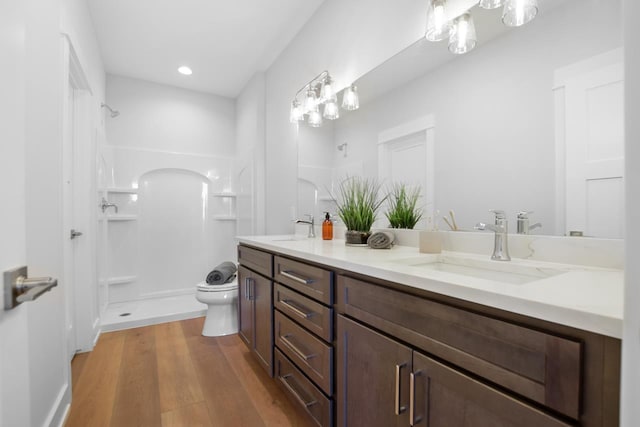 bathroom with hardwood / wood-style flooring, toilet, walk in shower, and vanity