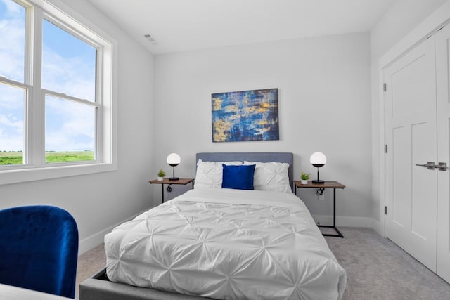 bedroom with light colored carpet and multiple windows