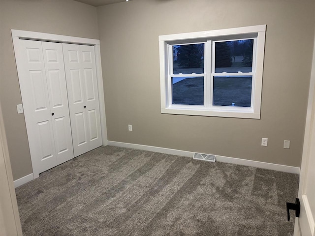 unfurnished bedroom featuring dark carpet and a closet