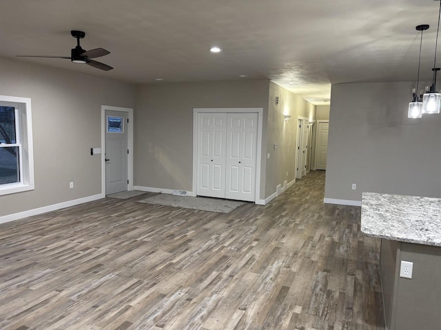 unfurnished living room with dark hardwood / wood-style flooring and ceiling fan