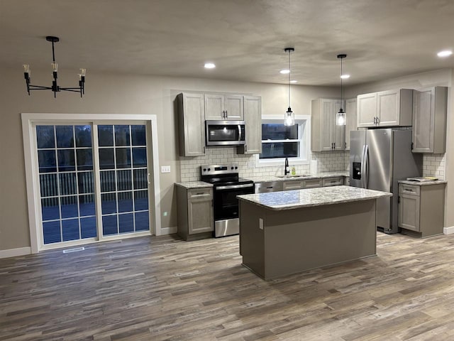 kitchen featuring a center island, sink, gray cabinets, decorative light fixtures, and stainless steel appliances