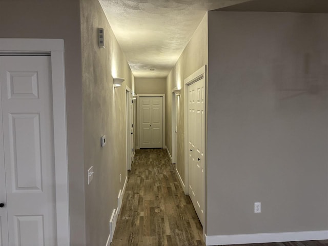 hallway featuring a textured ceiling and dark hardwood / wood-style flooring