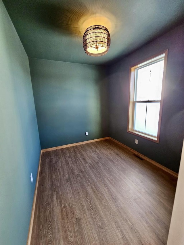 unfurnished room featuring visible vents, baseboards, and wood finished floors