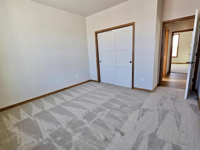 unfurnished bedroom with light colored carpet and a closet