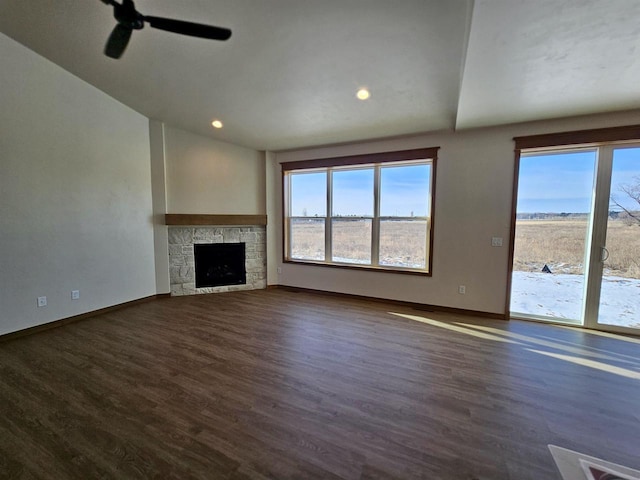 unfurnished living room featuring dark wood-style floors, a stone fireplace, and baseboards