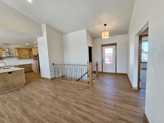 foyer with vaulted ceiling, wood finished floors, and baseboards