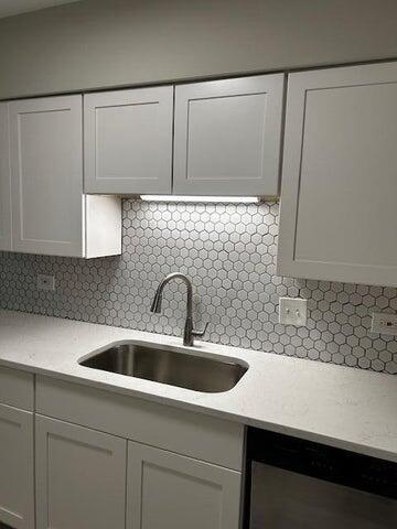 kitchen with white cabinets, tasteful backsplash, stainless steel dishwasher, and sink