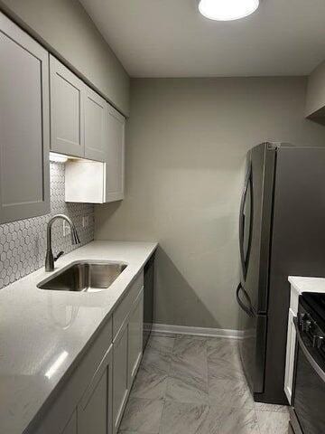 kitchen featuring backsplash, stainless steel refrigerator, sink, and black range with electric cooktop