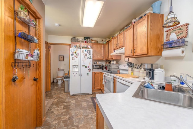 kitchen featuring white appliances, decorative light fixtures, and sink