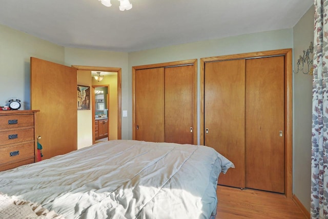 bedroom with light hardwood / wood-style floors and multiple closets