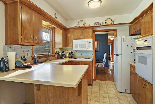 kitchen featuring kitchen peninsula, decorative backsplash, white appliances, and sink