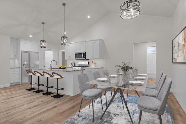 kitchen featuring white cabinets, range, decorative light fixtures, and a kitchen island with sink