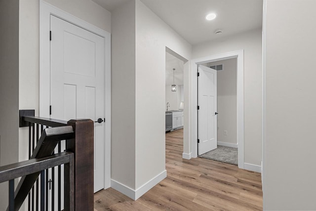 corridor with sink and light hardwood / wood-style floors