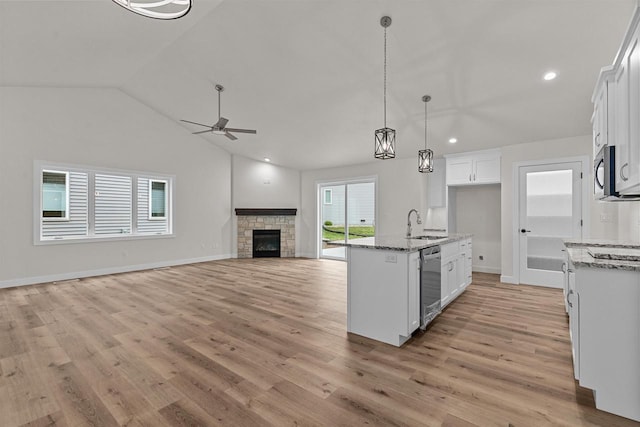 kitchen with a stone fireplace, white cabinetry, light stone counters, and appliances with stainless steel finishes