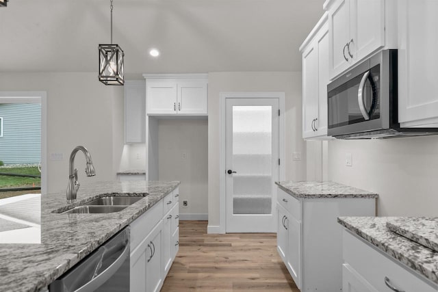 kitchen with white cabinetry, sink, decorative light fixtures, and appliances with stainless steel finishes