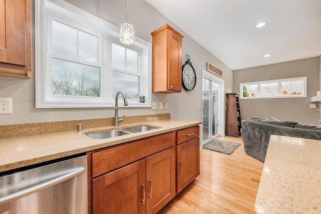 kitchen featuring dishwasher, sink, light stone counters, light hardwood / wood-style floors, and decorative light fixtures