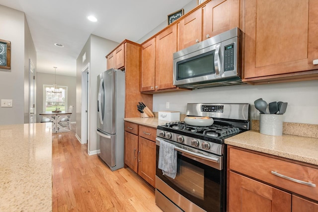 kitchen with pendant lighting, a notable chandelier, light stone counters, and stainless steel appliances