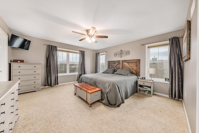 bedroom with ceiling fan, light carpet, and multiple windows