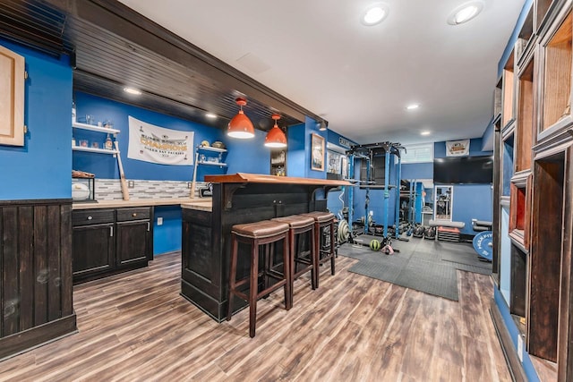 bar featuring pendant lighting, backsplash, and hardwood / wood-style flooring