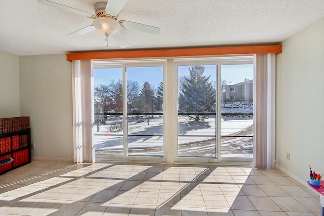 entryway with ceiling fan, a textured ceiling, and light tile patterned flooring