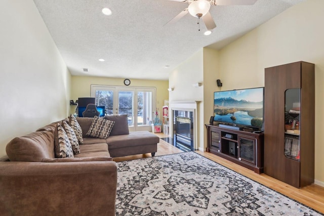 living room featuring ceiling fan, a textured ceiling, and light wood-type flooring