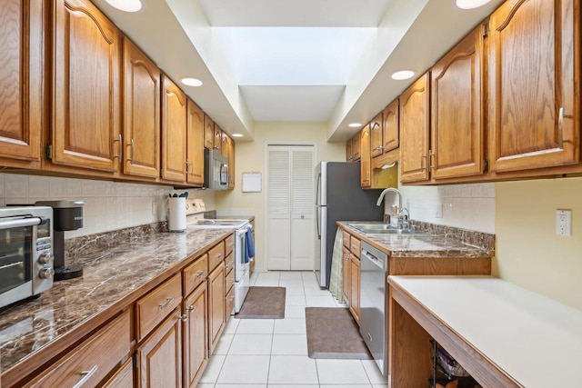 kitchen featuring sink, light tile patterned floors, stainless steel appliances, and decorative backsplash