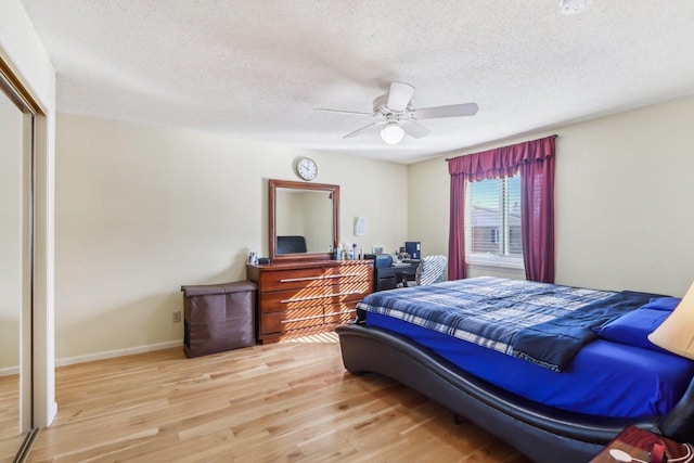 bedroom featuring a textured ceiling, light hardwood / wood-style floors, a closet, and ceiling fan