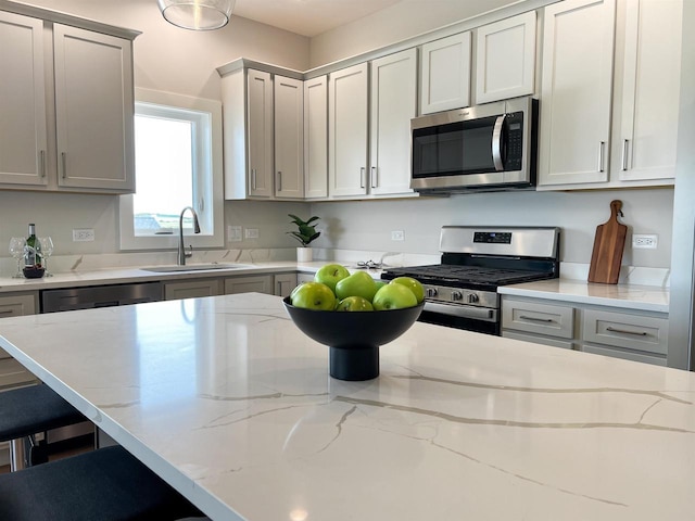 kitchen with light stone countertops, stainless steel appliances, gray cabinetry, and sink