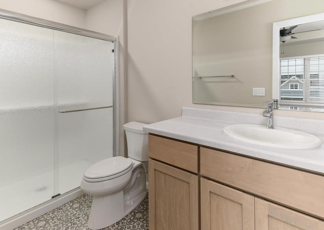 bathroom with a stall shower, vanity, toilet, and a ceiling fan