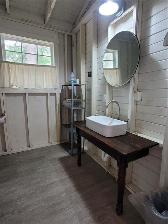 interior space featuring sink, vaulted ceiling with beams, and wood walls