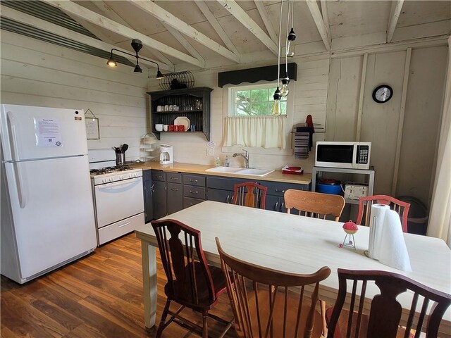 kitchen with sink, hanging light fixtures, vaulted ceiling with beams, dark hardwood / wood-style flooring, and white appliances