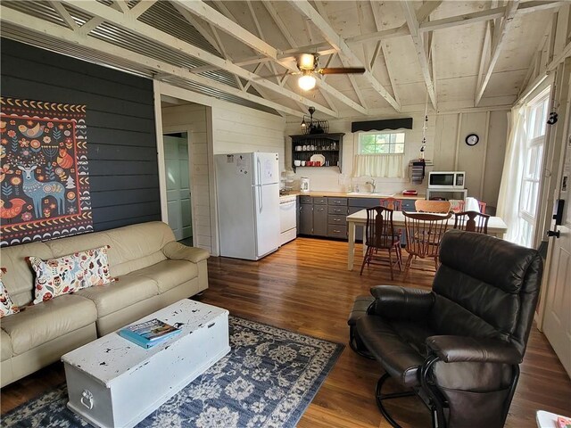 living room with ceiling fan, wood-type flooring, sink, and wooden walls